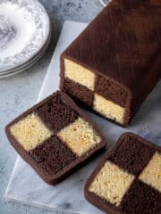 Chocolate orange Battenberg cake on a marble board with two slices cut.