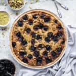Pistachio cherry frangipane tart with bowls of cherry jam, pistachios and ground pistachios.