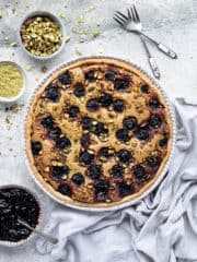 Pistachio cherry frangipane tart with bowls of cherry jam, pistachios and ground pistachios.