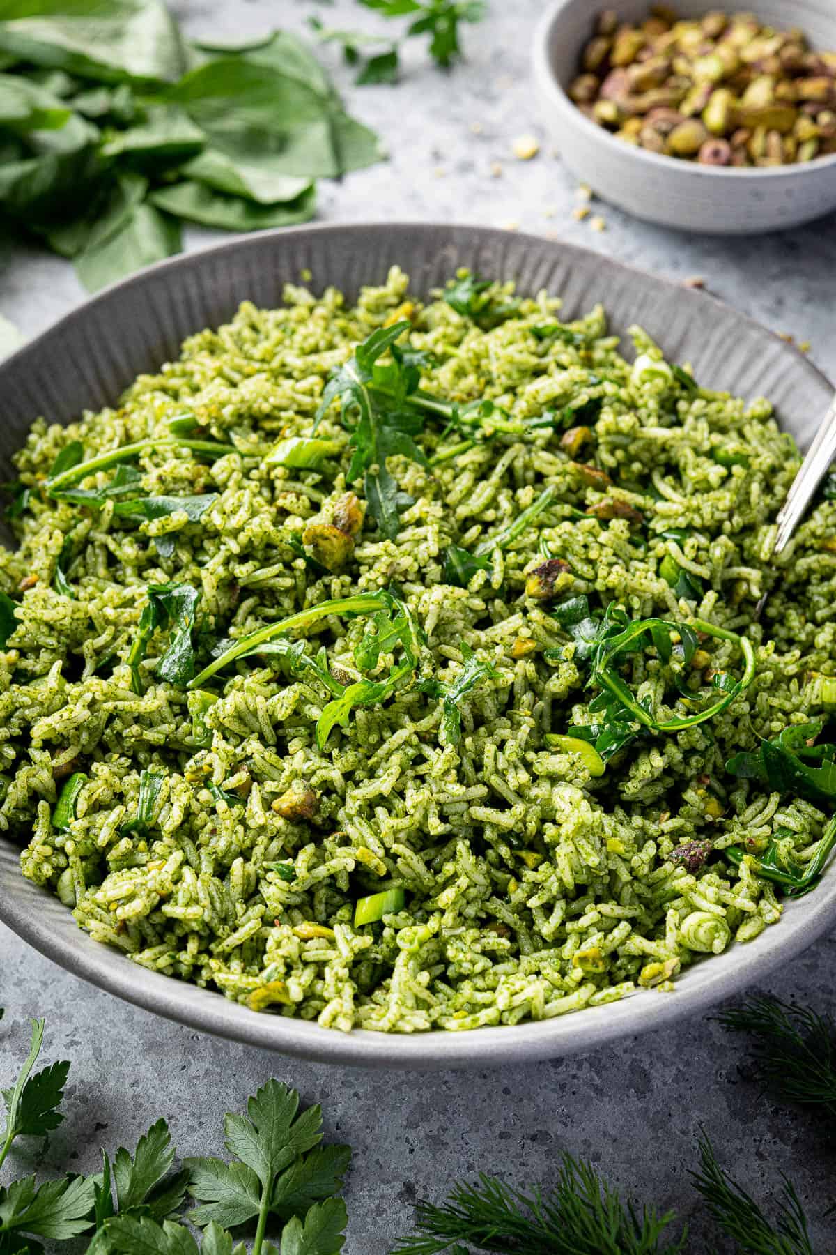 A bowl of herby rice on a grey background.