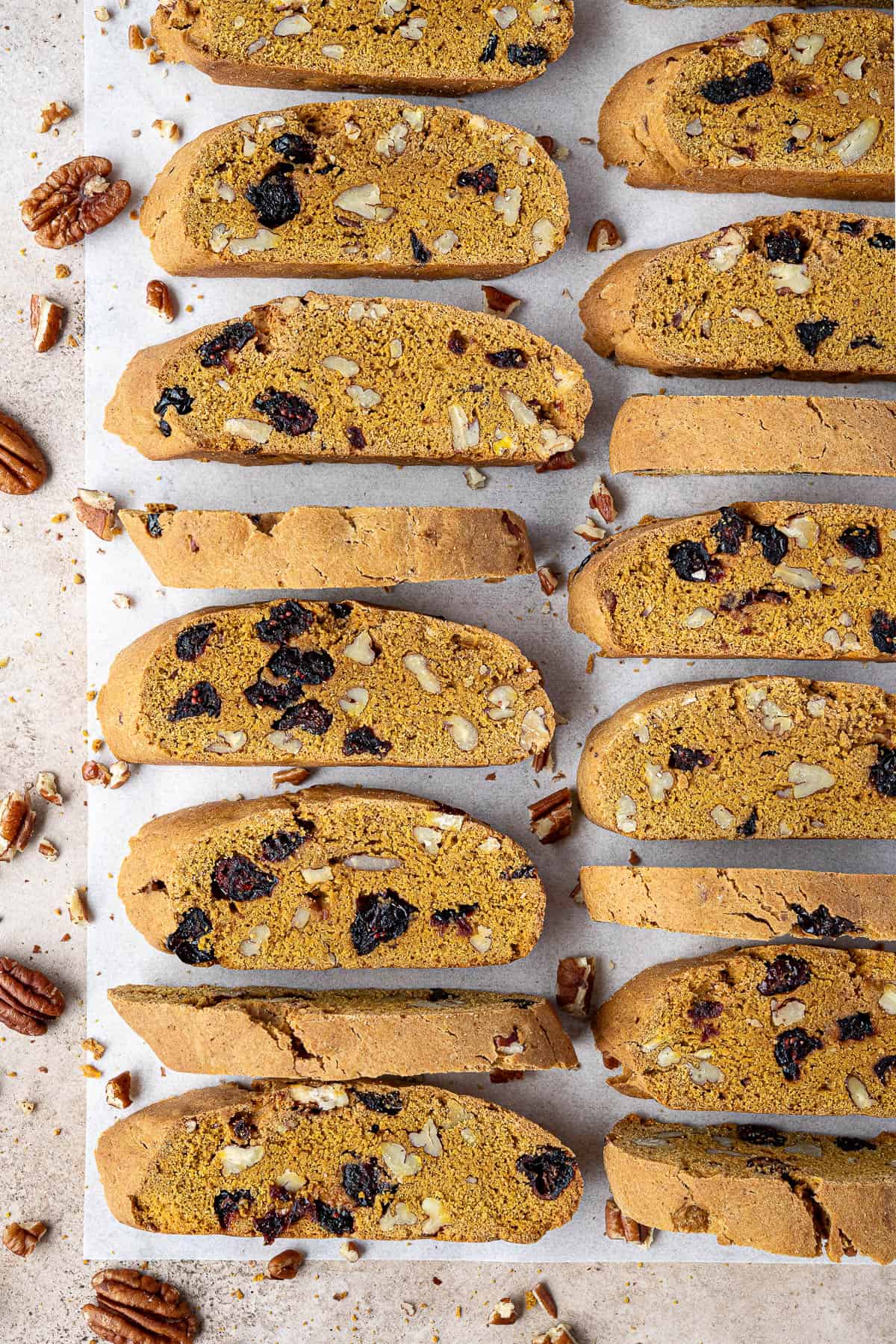 Two rows of vegan pumpkin biscotti on a sheet of baking parchment.