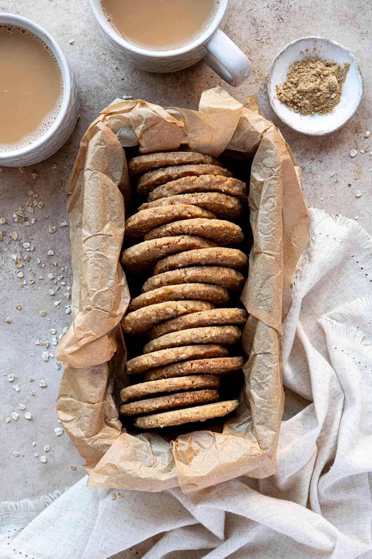 Spiced oat biscuits in a parchment lined loaf tin with cups of tea.
