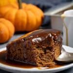 A square of vegan pumpkin sticky toffee pudding on a plate with a spoonful removed.