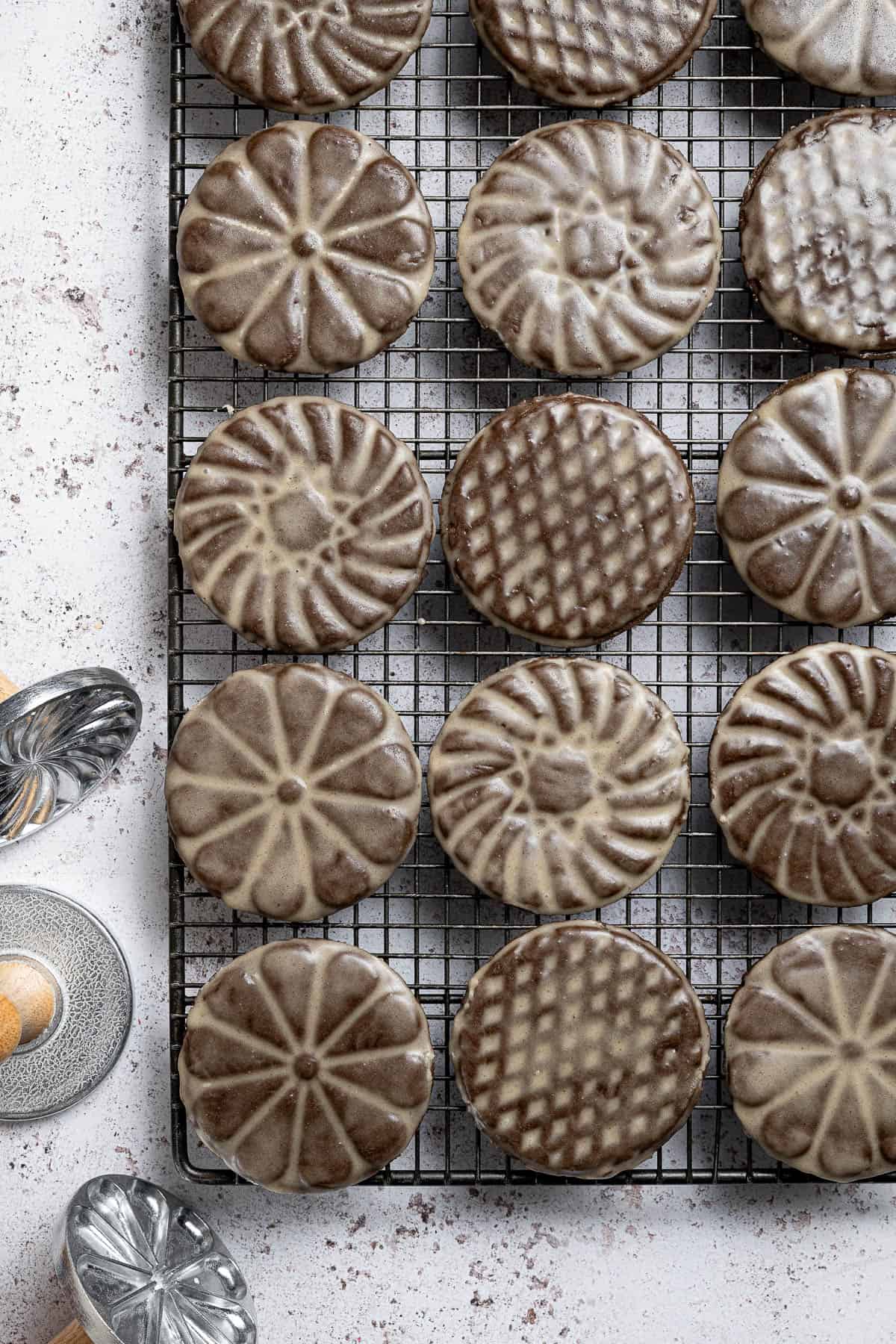 Vegan glazed gingerbread cookies on a wire cooling rack with some metal cookie stamps next to it.