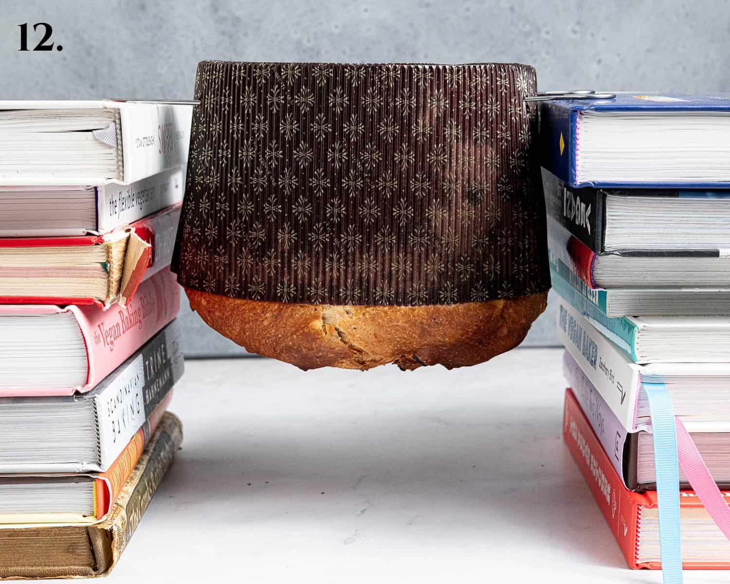 Step 12, the skewered panettone hung upside-down between two stacks of books.