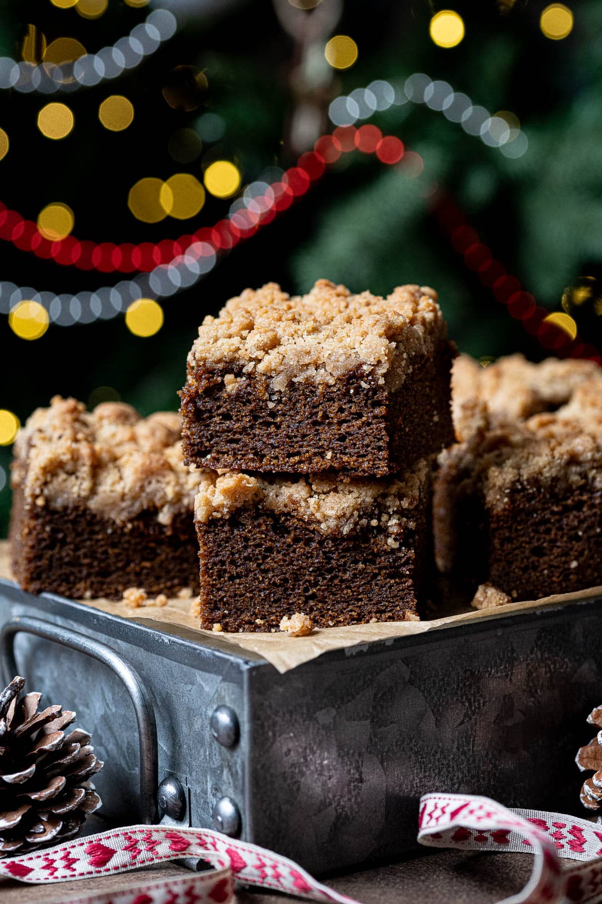 Squares of gingerbread crumble cake on a festive background with Christmas lights.