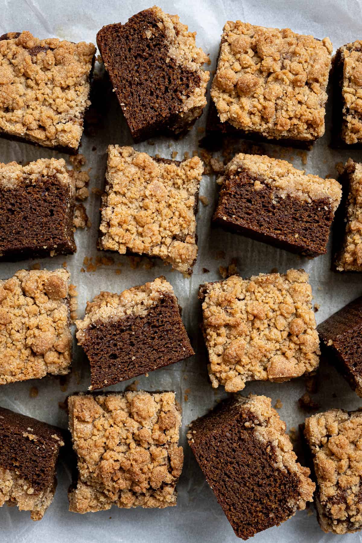 Squares of vegan gingerbread crumb cake on a sheet of baking paper.