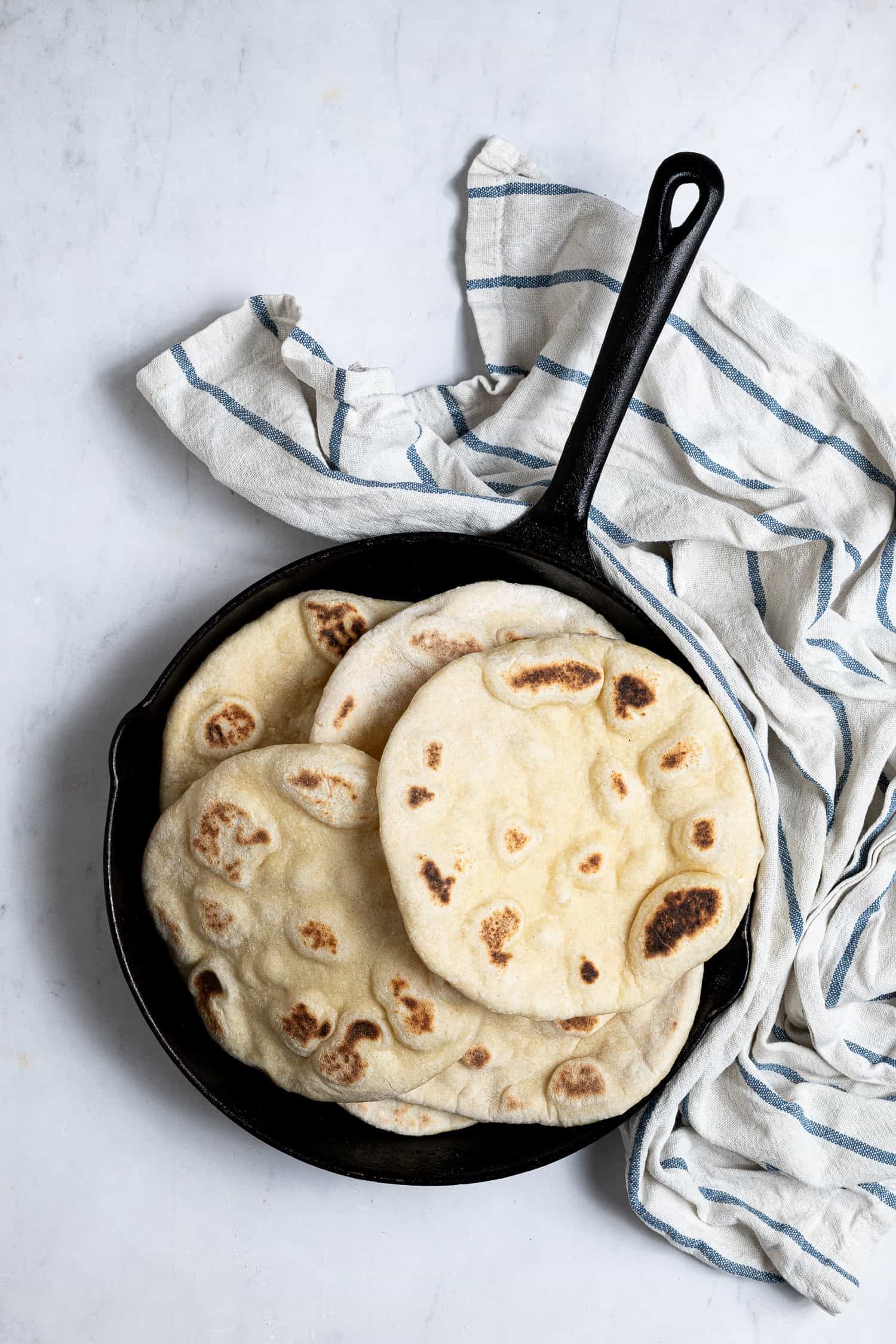 Vegan yogurt flatbreads piled up in a skillet.