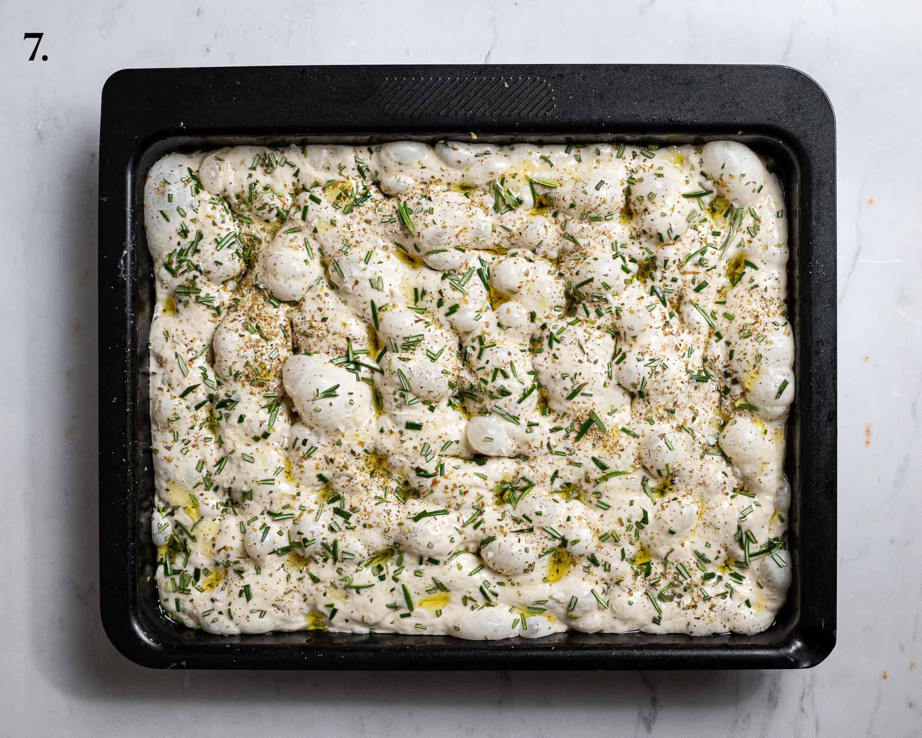Step 7, the dimpled dough topped with olive oil, herbs and salt.