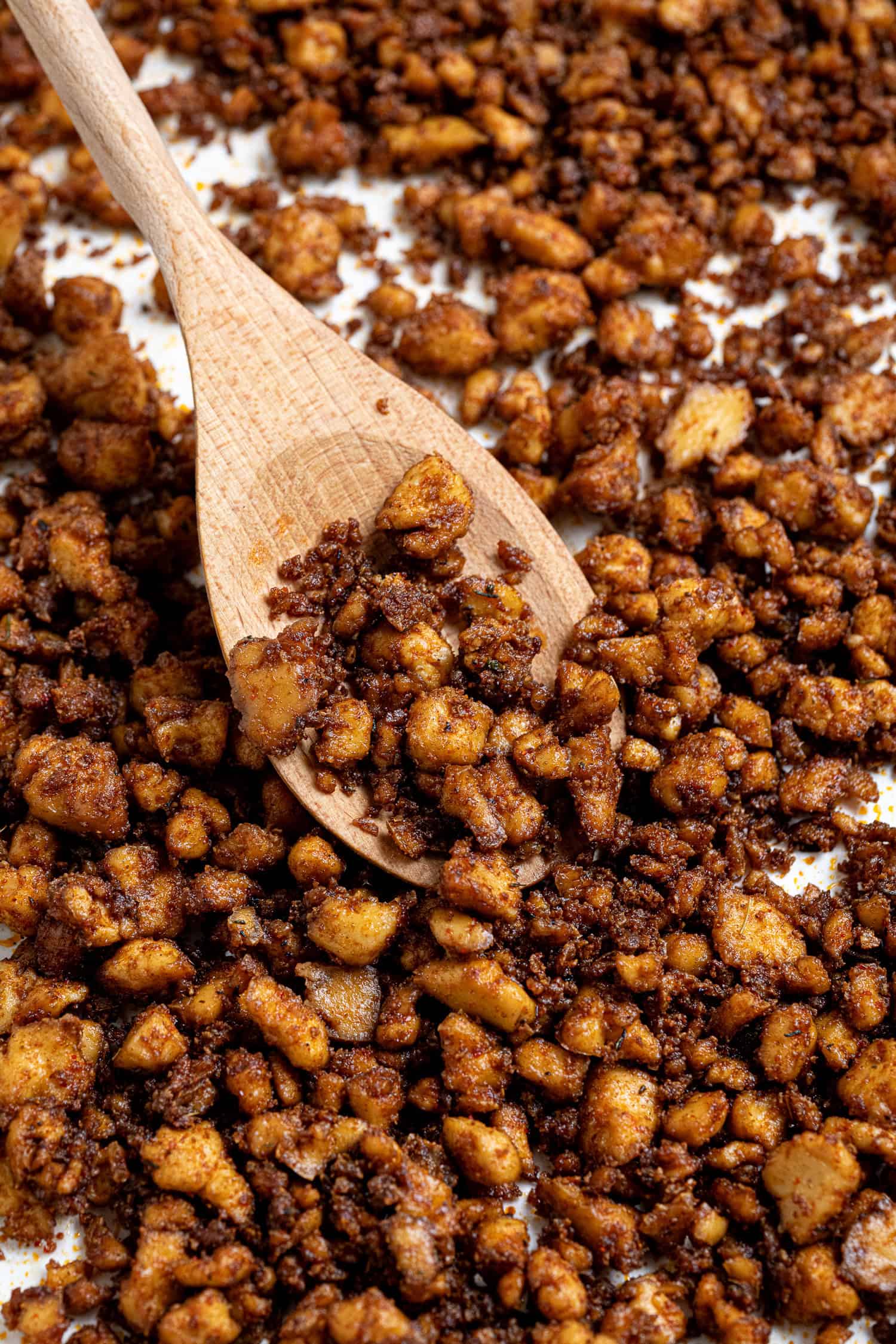 Close up of baked tofu crumbles with a wooden spoon.