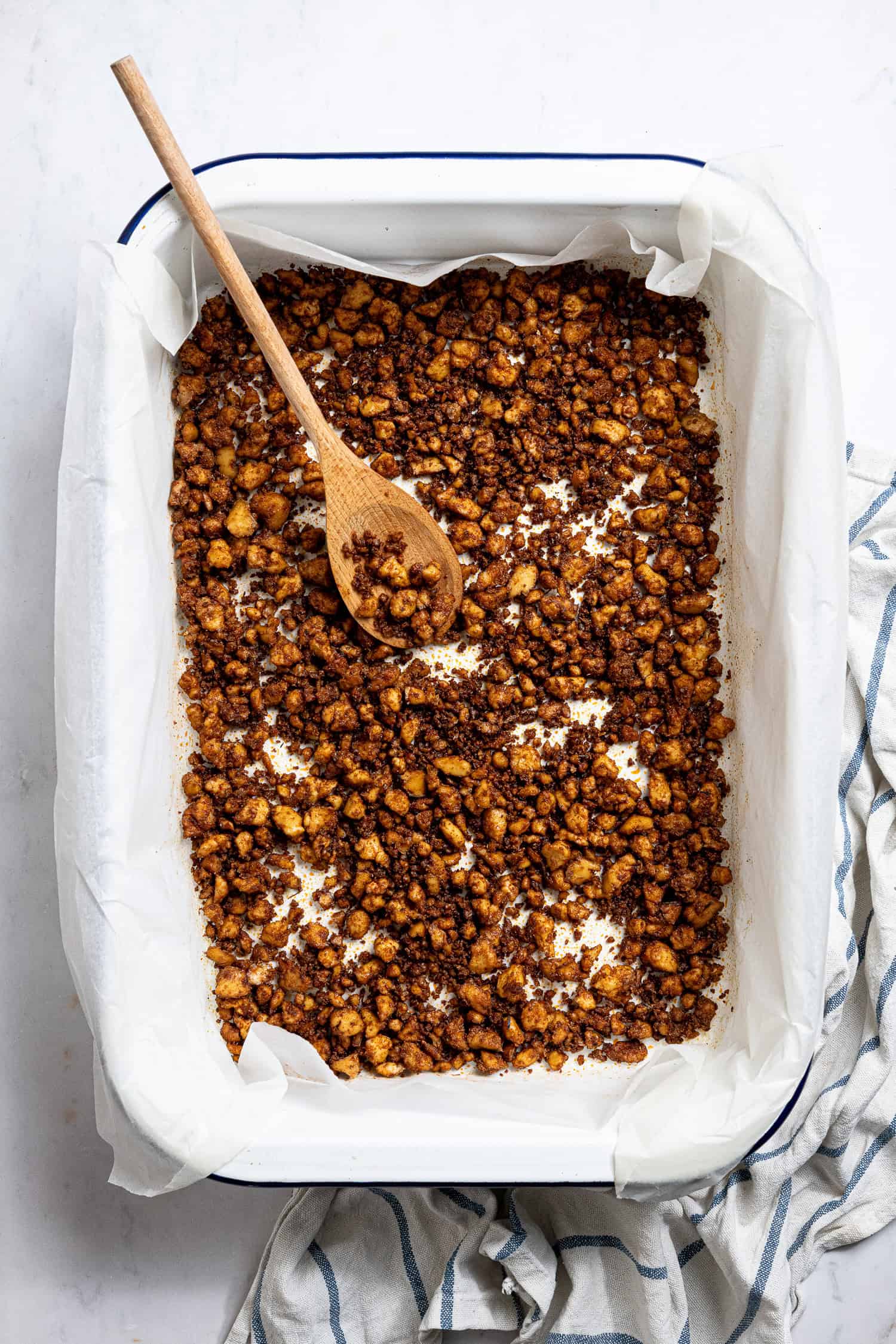 A parchment lined roasting tin full of baked tofu crumbles.