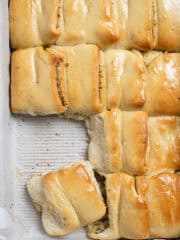 Close up of vegan garlic Parker House rolls in the pan with a couple removed.