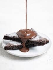 Chocolate custard being poured onto a plate with two slices of vegan chocolate concrete.