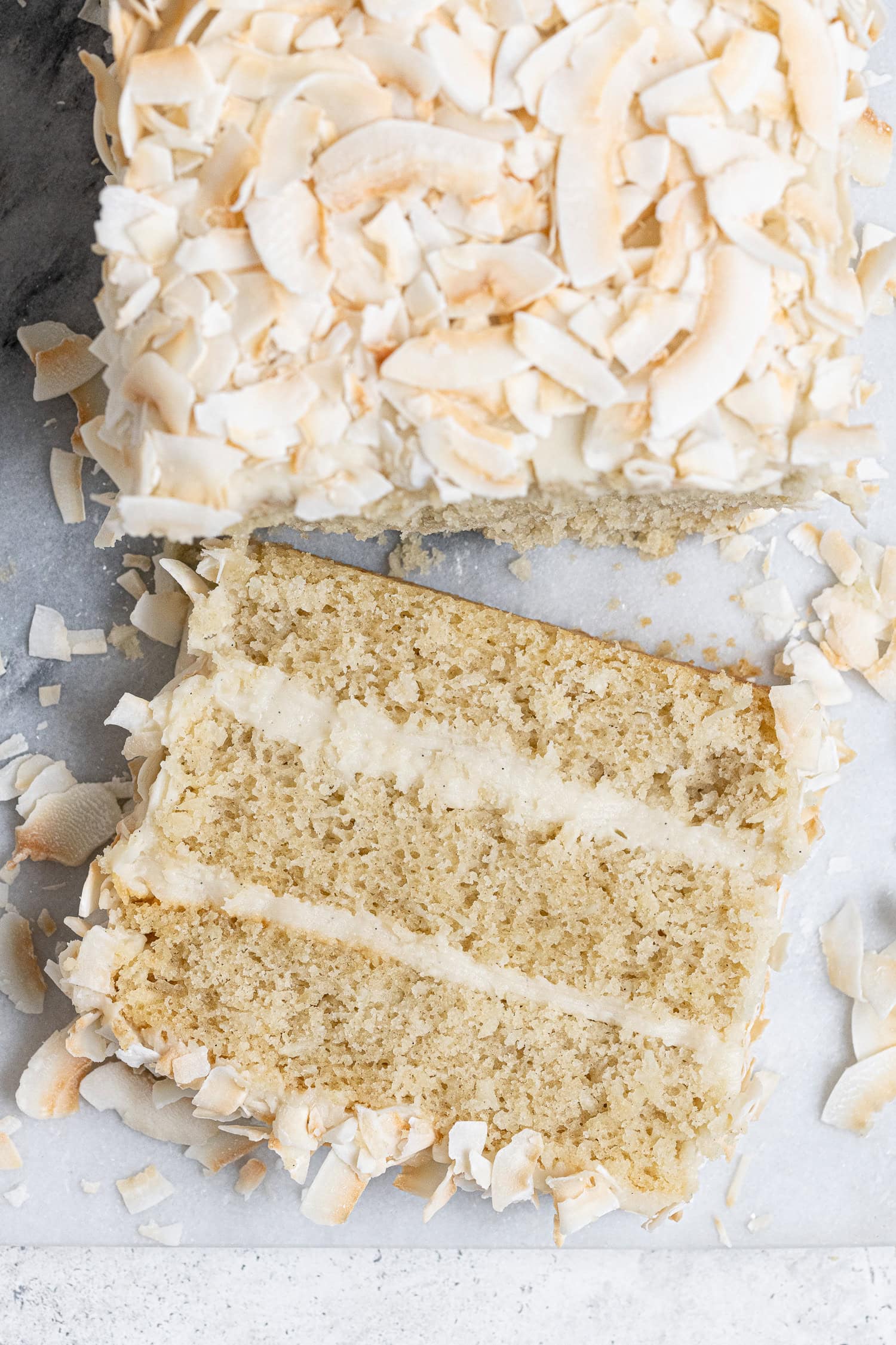A slice of vegan coconut cream cake on a marble board.