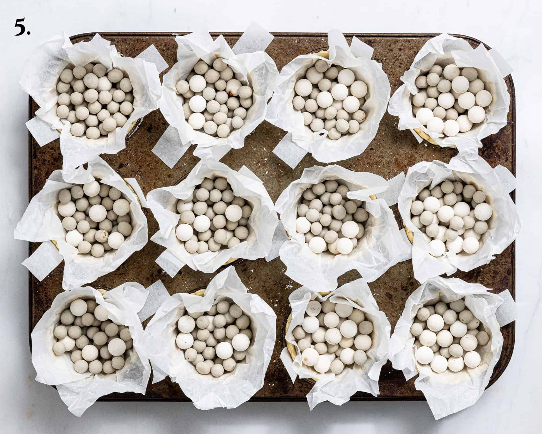 Step 5, the pastry cases lined with baking paper and beans.