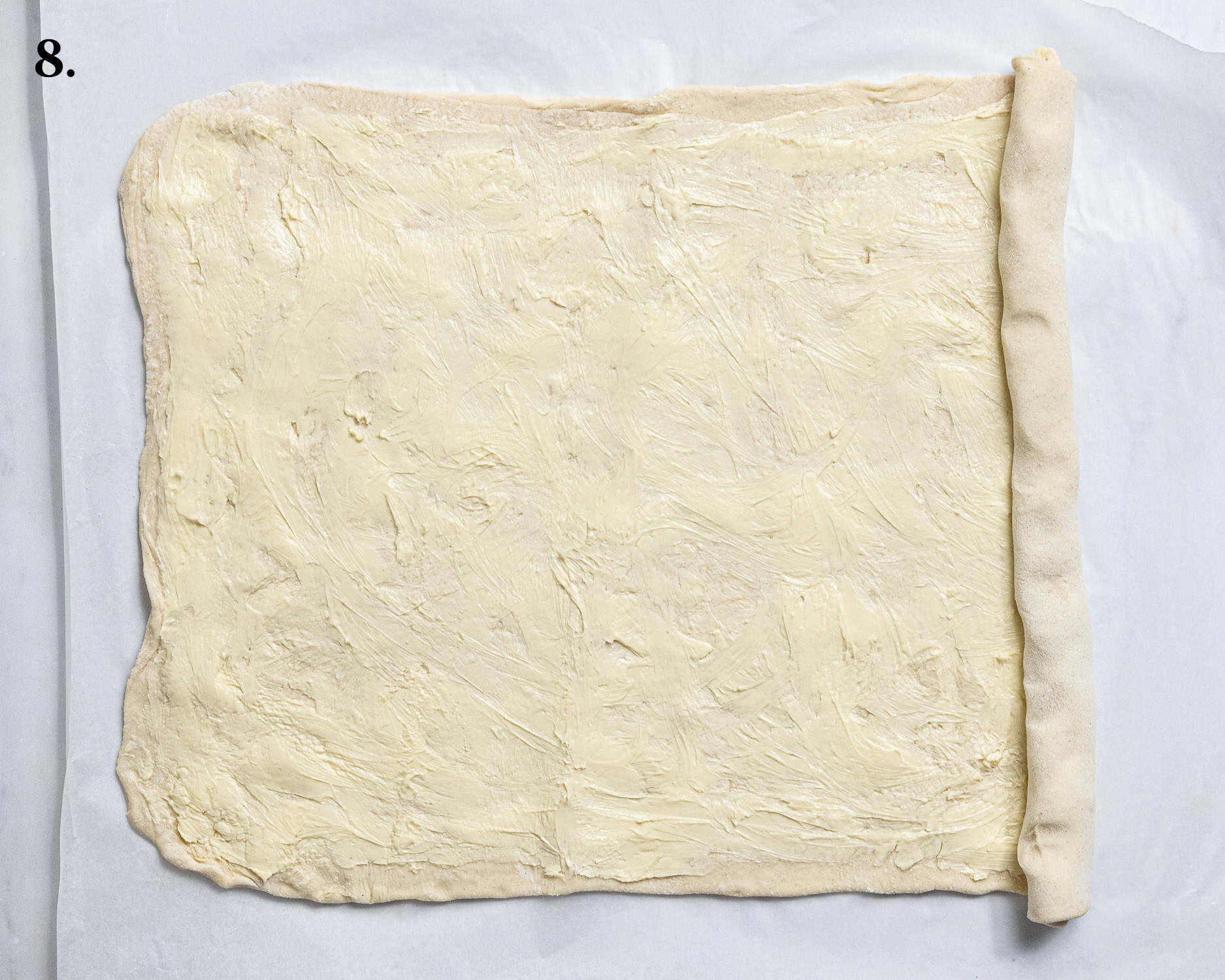 Step 8, the rolled out pastry spread with butter being rolled up into a log.