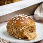 An oatmeal molasses roll on a white plate.