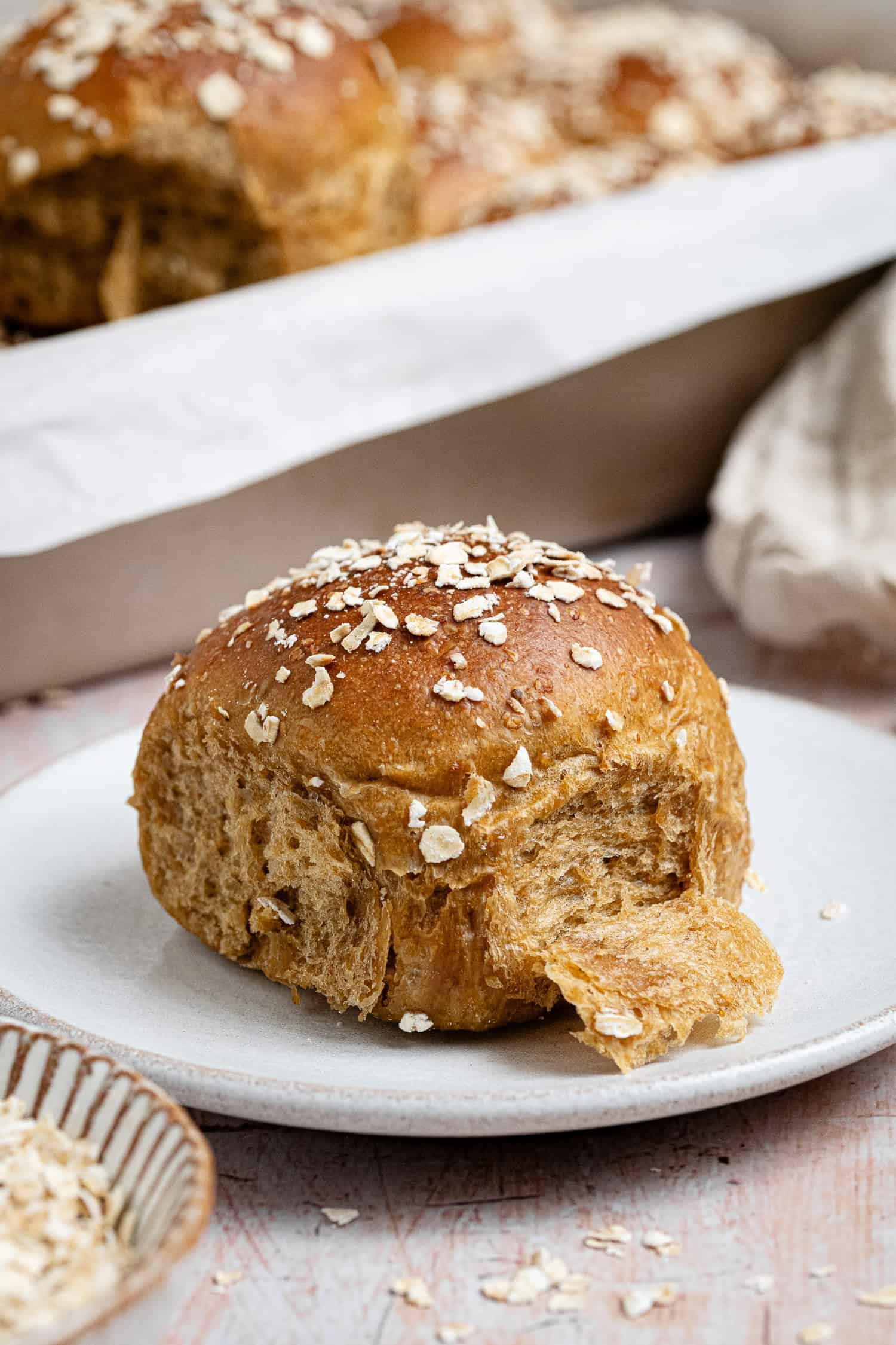 An oatmeal molasses roll on a white plate.
