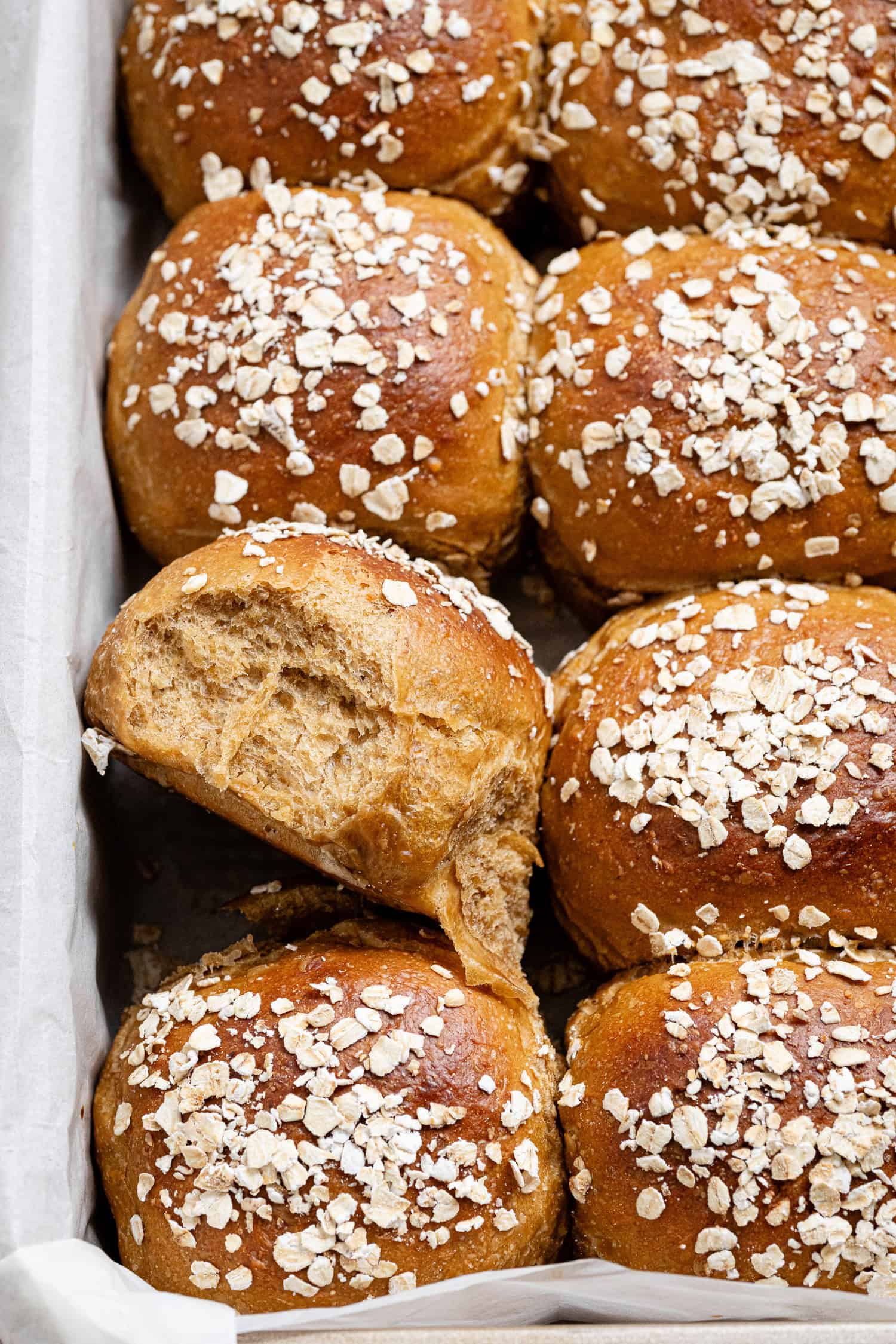 Close up shot of a pan of oatmeal molasses rolls, one turned on it's side.