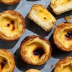 Flatlay of vega pasteis de nata on a grey surface, one sliced in half.