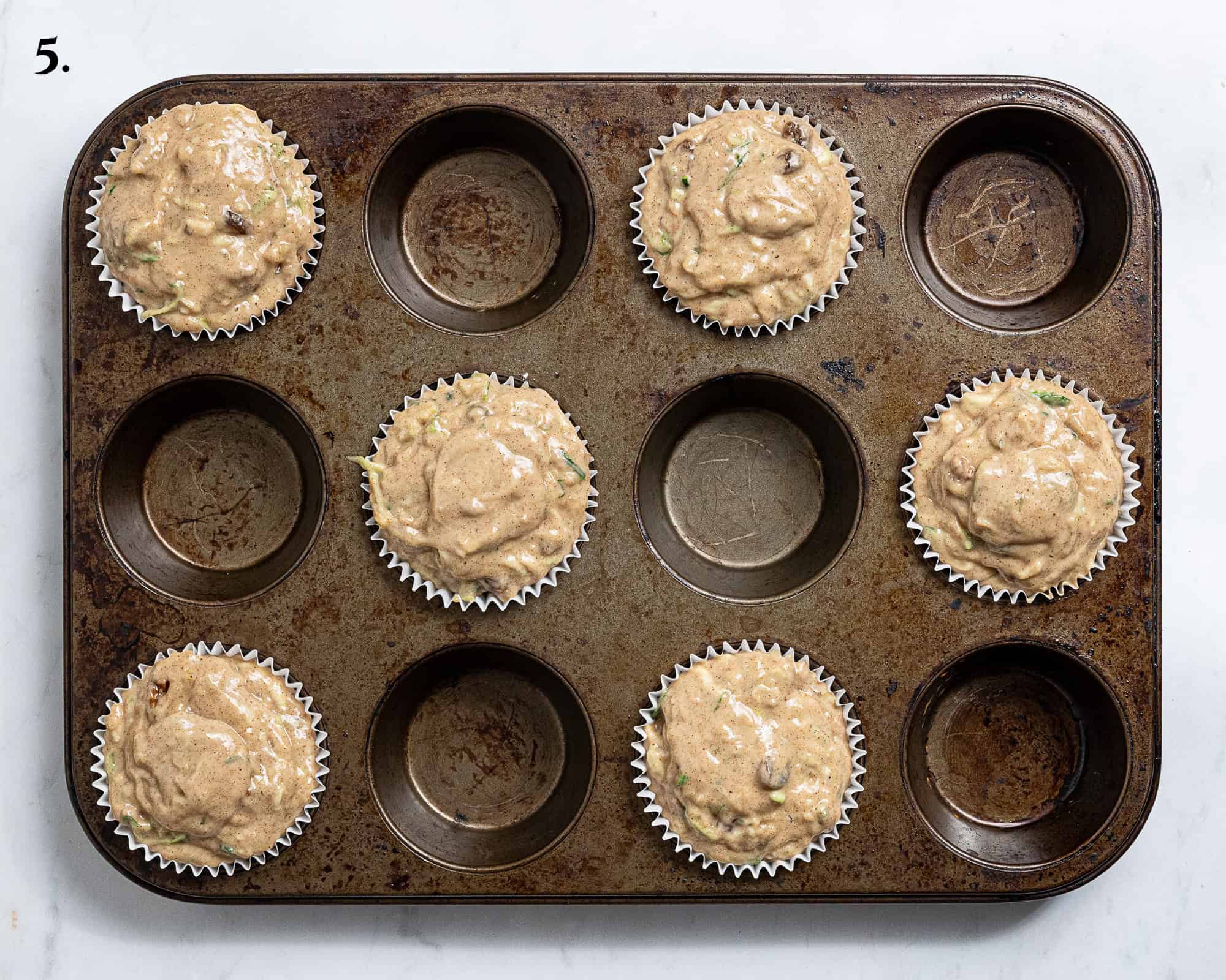 Step 5, the batter divided between the muffin cases.