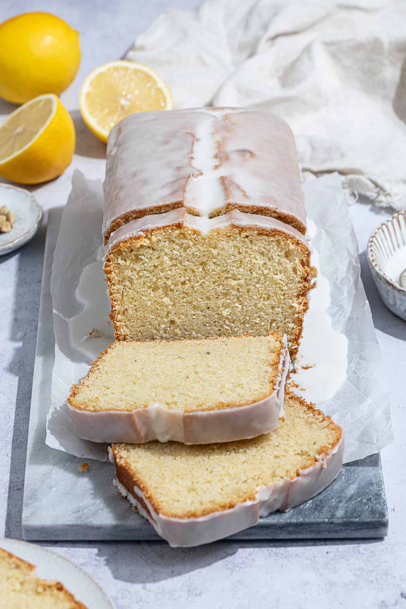 Sliced vegan lemon cardamom pound cake on a marble board.