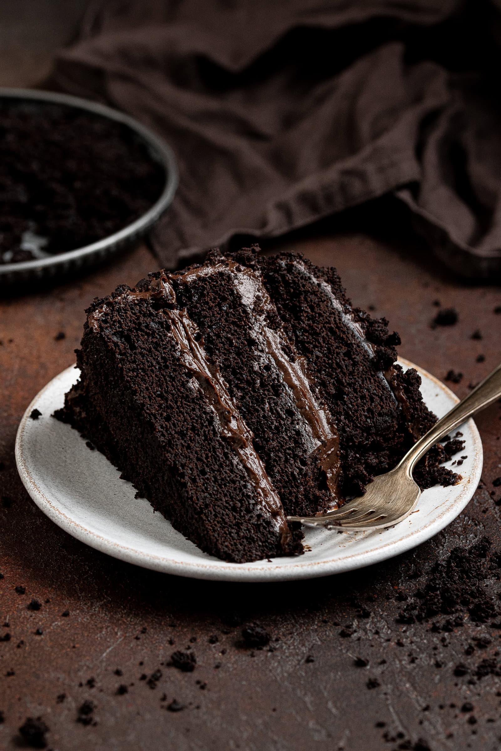A slice of vegan Brooklyn blackout cake on a white plate with a forkful removed.