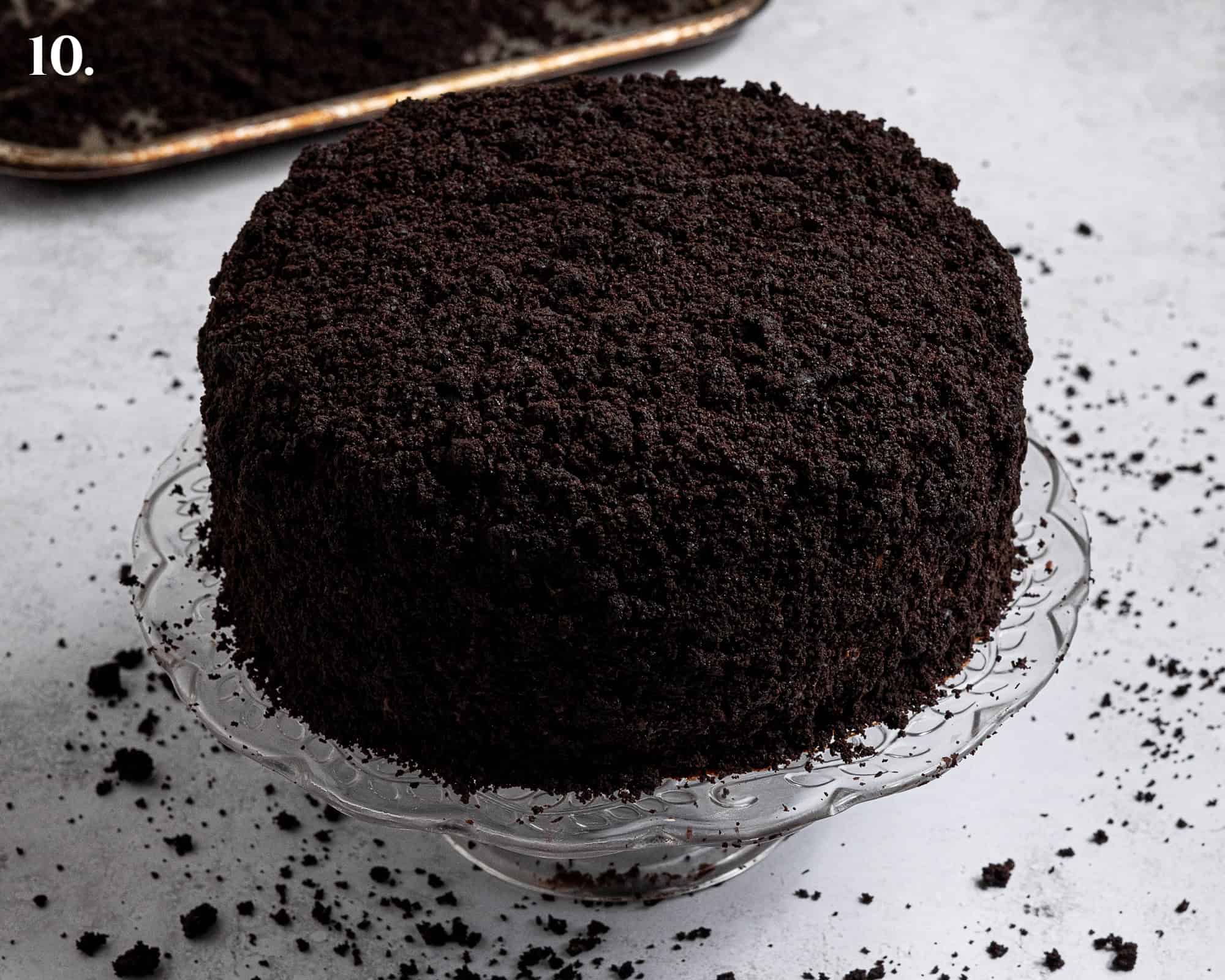 Step 10, the crumb coated cake on a cake stand.