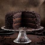 Sliced vegan Brooklyn blackout cake on a glass cake stand.