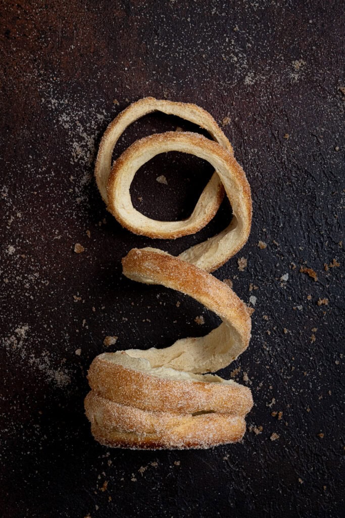 An unravelled vegan chimney cake on a dark surface.