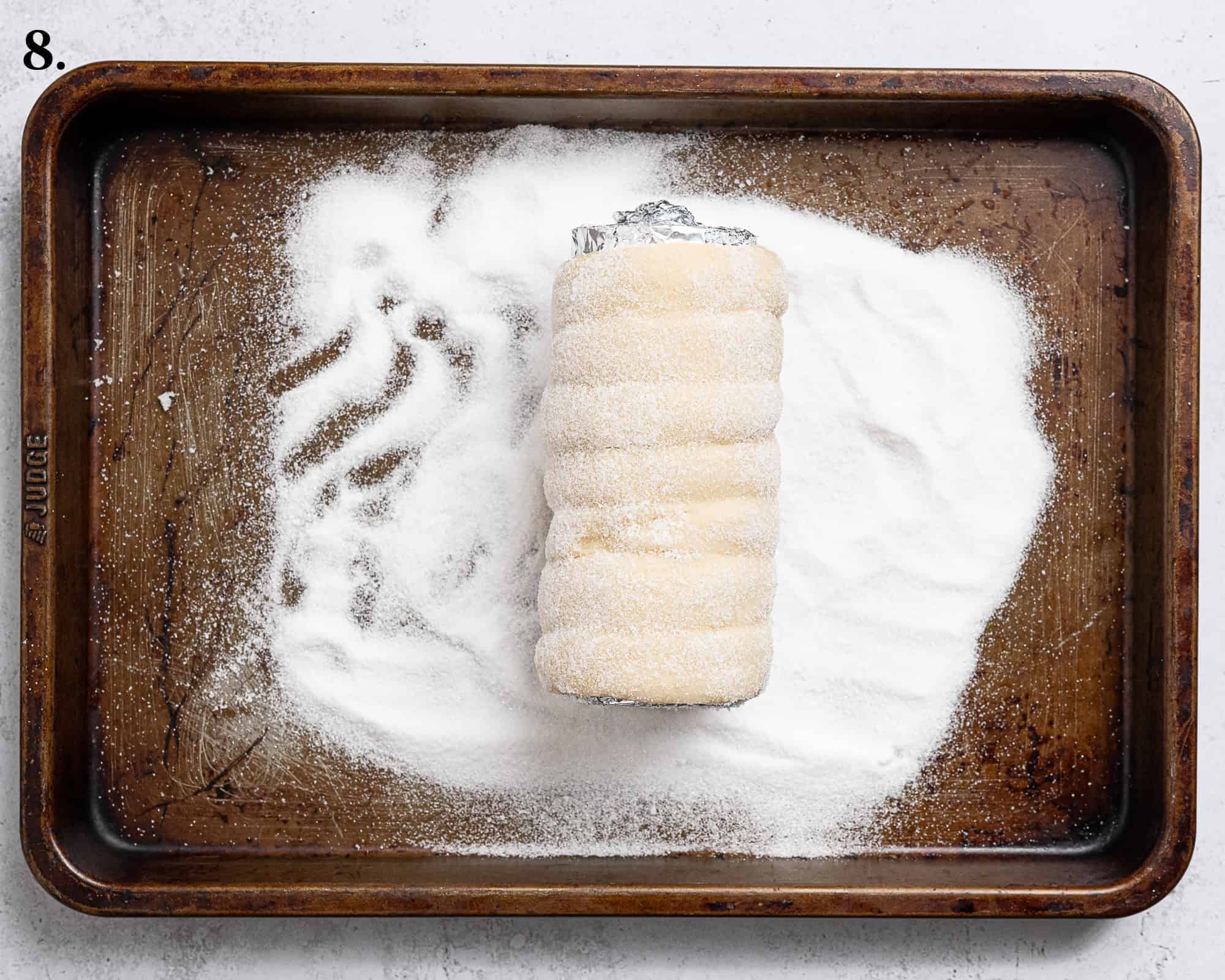 Step 8, an unbaked chimney cake being rolled in sugar.