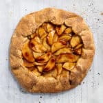 The baked and glazed vegan apple galette on a sheet of baking paper.