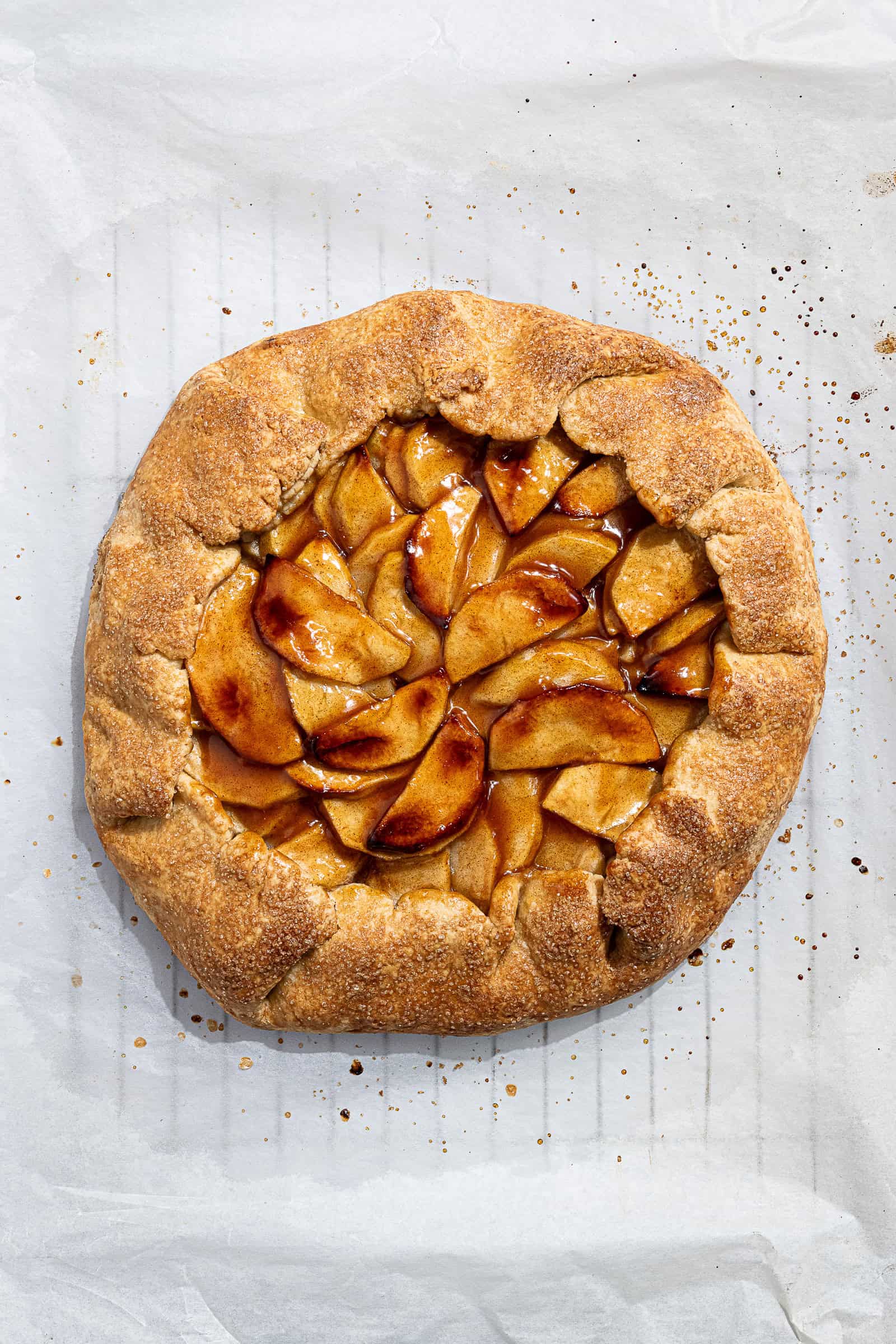 The baked and glazed vegan apple galette on a sheet of baking paper.
