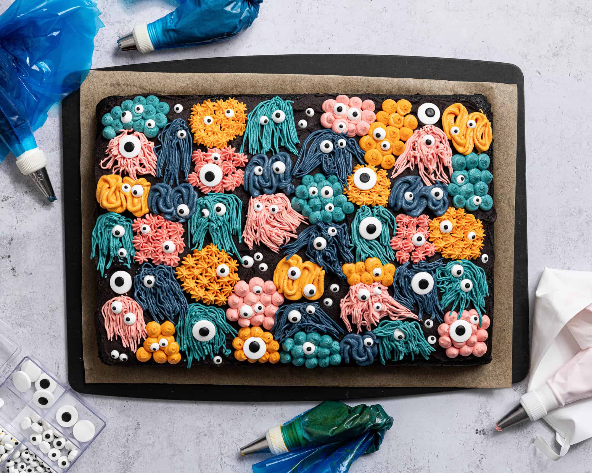 The decorated monster cake with the piping bags of buttercream around it.