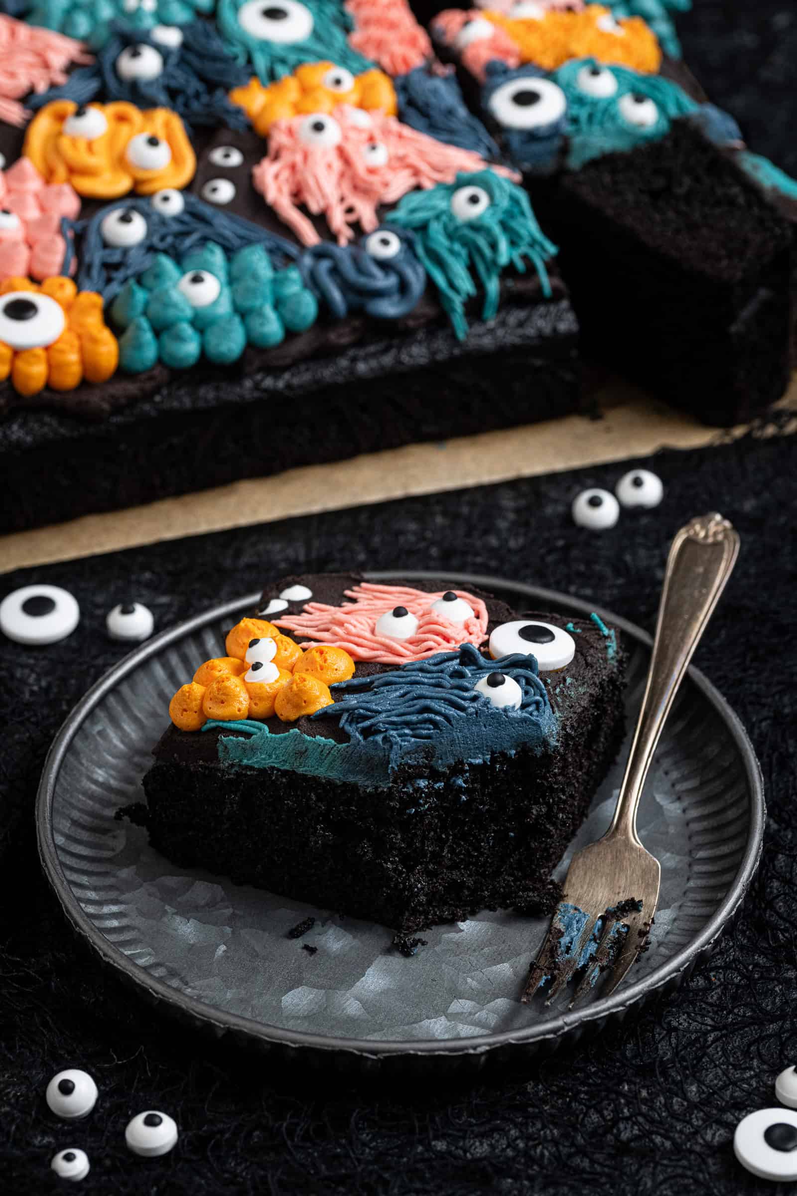 A slice of vegan black velvet sheet cake on a metal plate with a fork.