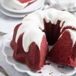 Vegan red velvet bundt cake on a white plate with a couple of slices cut out.